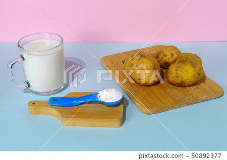Powdered vegan potato milk. A glass of milk on a multicolored background Powdered vegan potato milk. A glass of milk on a multicolored background 80892377