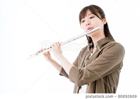 A woman playing the flute in a casual outfit A woman playing the flute in a casual outfit 80892609