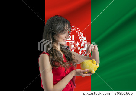 Economy in Afghanistan. Accumulating and saving money in Afghanistan. Woman putting money coin in piggy bank for saving money and plan finance Economy in Afghanistan. Accumulating and saving money in Afghanistan. Woman putting money coin in piggy bank for saving money and plan finance 80892660
