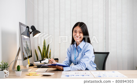 Asian women sit at their desks and calculate financial graphs showing results about their investments, plan a successful business growth process Asian women sit at their desks and calculate financial graphs showing results about their investments, plan a successful business growth process 80894303
