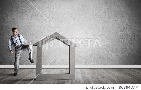 Stone home silhouette in empty room as symbol for real estate insurance 80894377