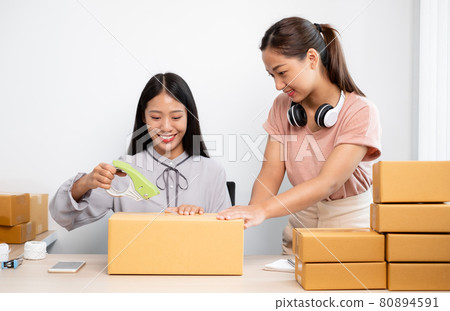 An Asian businesswoman, two owners with lots of boxes on their desks, happy to sell online, take orders from customers, and arrange their mail delivery An Asian businesswoman, two owners with lots of boxes on their desks, happy to sell online, take orders from customers, and arrange their mail delivery 80894591