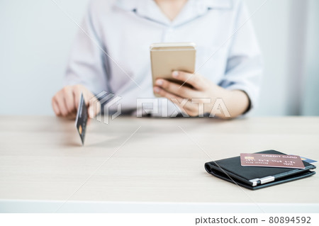 The businesswoman's hand is holding a credit card and using a smartphone for online shopping and internet payment in the office 80894592