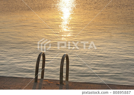 寧靜無人居住的小漁港,夕陽的光芒反射在平靜的海面上。 寧靜無人居住的小漁港,夕陽的光芒反射在平靜的海面上。 80895887