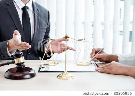 A male lawyer or a judge counseling clients about judicial justice and prosecution with scales, judges gavel, legal documents legal services concept 80895936