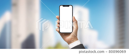 在摩天大樓區拿著智能手機的商人 80896069