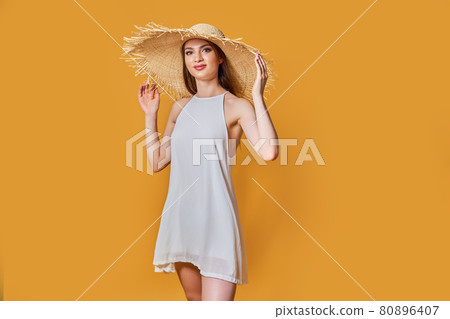 Pretty glamorous girl touching her straw hat. Studio portrait of joyful young woman Pretty glamorous girl touching her straw hat. Studio portrait of joyful young woman 80896407