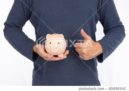 Man holding a pink piggy bank and showing thumbs up isolated on white background Man holding a pink piggy bank and showing thumbs up isolated on white background 80898342