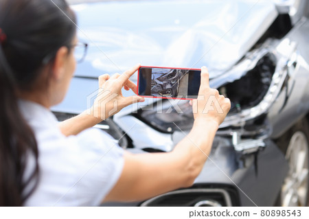 Woman agent takes pictures of damage to car after accident by smartphone 80898543