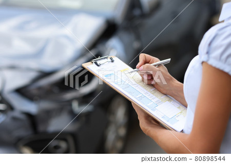 Insurance agent conducts inspection of the damaged car by filling out documents 80898544