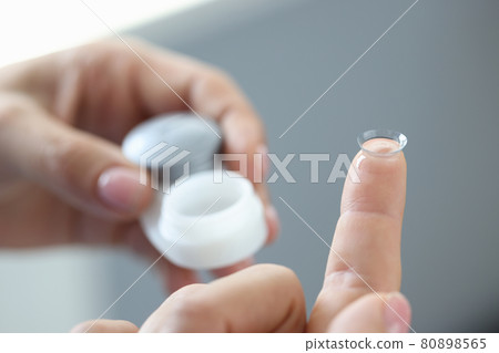 New clear contact lens on finger closeup 80898565