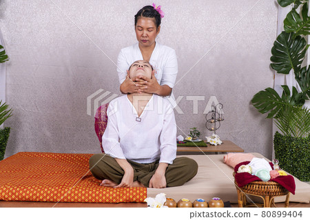 Wellness of relaxed Asian young woman massaging elbow and arm by professional massager in spa salon. Wellness of relaxed Asian young woman massaging elbow and arm by professional massager in spa salon. 80899404