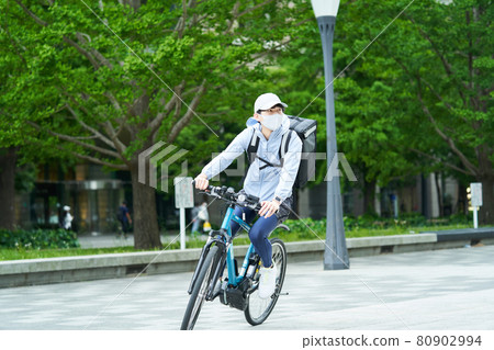 A man riding a bicycle and delivering in the city A man riding a bicycle and delivering in the city 80902994