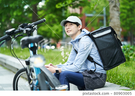 一個騎自行車在城里送貨的人 80903005