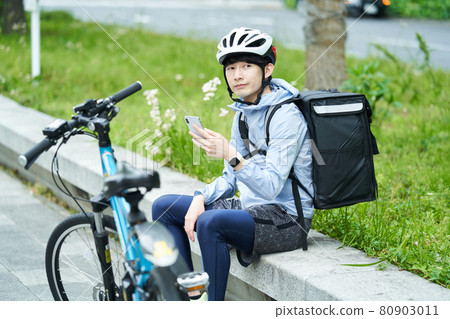 一個騎自行車在城里送貨的人 80903011