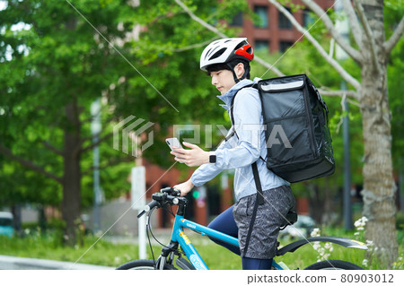 A man riding a bicycle and delivering in the city 80903012