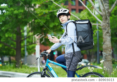 A man riding a bicycle and delivering in the city 80903013