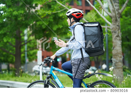 一個騎自行車在城里送貨的人 80903016