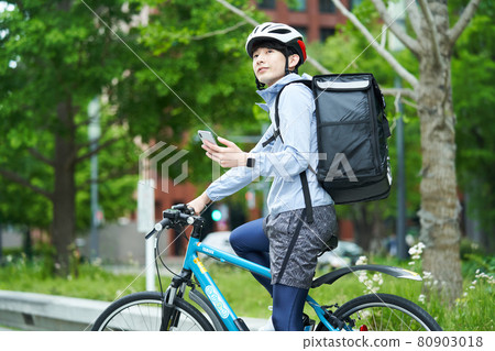 A man riding a bicycle and delivering in the city 80903018