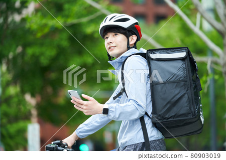 A man riding a bicycle and delivering in the city 80903019