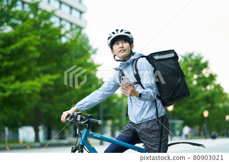 A man riding a bicycle and delivering in the city A man riding a bicycle and delivering in the city 80903021