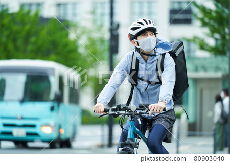 一個騎自行車在城里送貨的人 80903040
