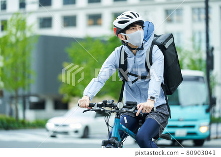 A man riding a bicycle and delivering in the city A man riding a bicycle and delivering in the city 80903041