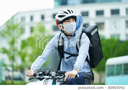 一個騎自行車在城里送貨的人 80903042