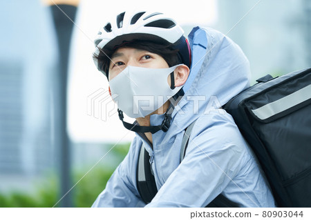 一個騎自行車在城里送貨的人 80903044