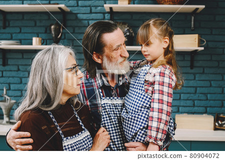 Senior grandparents couple with dgranddaughter cooking in kitchen 80904072