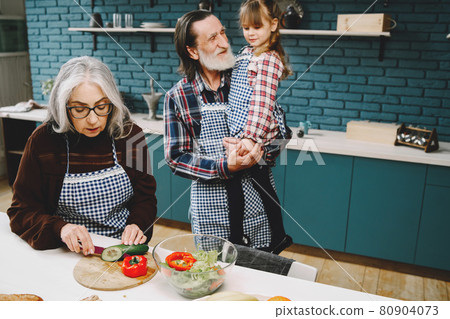 Senior grandparents couple with dgranddaughter cooking in kitchen Senior grandparents couple with dgranddaughter cooking in kitchen 80904073