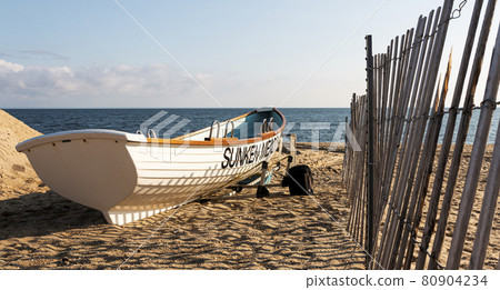 White lifeguards row boat on the sand next to a fence at Sunken Meadow State Park White lifeguards row boat on the sand next to a fence at Sunken Meadow State Park 80904234