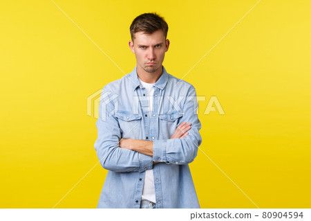 Lifestyle, people emotions and summer leisure concept. Angry offended, grumpy blond guy cross arms chest insulted, looking from under forehead and frowning displeased, feel mad, yellow background 80904594