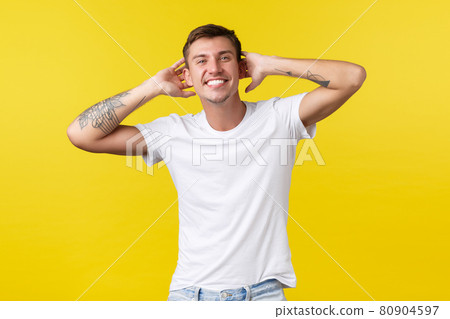 Lifestyle, summer and people emotions concept. Carefree handsome happy man with white cheerful smile, holding hands behind head, enjoying vacation, standing yellow background Lifestyle, summer and people emotions concept. Carefree handsome happy man with white cheerful smile, holding hands behind head, enjoying vacation, standing yellow background 80904597