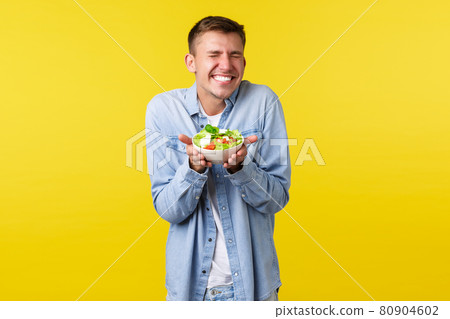 Healthy lifestyle, people and food concept. Excited, extremely happy handsome blond man smiling with closed eyes, rejoicing as prepared delicious salad, standing yellow background Healthy lifestyle, people and food concept. Excited, extremely happy handsome blond man smiling with closed eyes, rejoicing as prepared delicious salad, standing yellow background 80904602