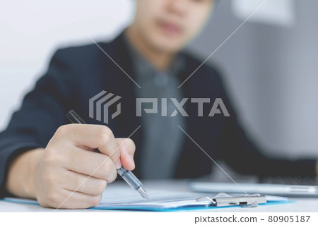 Business partners concept a young businessman holding a pen pointing at profit summary of the recent month showing in document forms 80905187