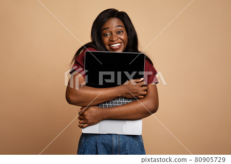 Delighted young black woman enjoying her new modern laptop Delighted young black woman enjoying her new modern laptop 80905729