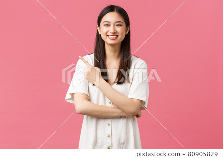 Beauty, people emotions and summer leisure concept. Attractive happy asian girl in cute dress, pointing finger upper left corner and laughing as advertising product or shopping mall promo offer 80905829
