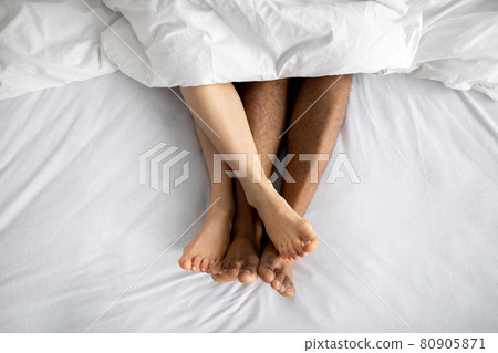 Top view of young multiracial couple lying in bed after lovemaking. Erotic games, sexual foreplay, intimate relationship 80905871