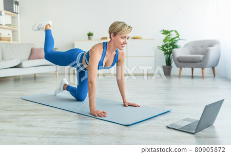 Smiling Woman In Sportswear Doing Donkey Kicks Exercise 80905872