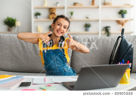 Girl sitting at desk, using pc, showing thumbs up 80905888