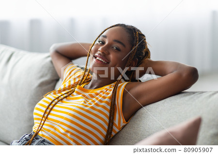 Closeup of happy black woman reclining on couch at home 80905907