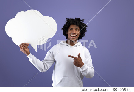 Funky black teen guy pointing at empty speech bubble, smiling at camera on violet studio background, mockup Funky black teen guy pointing at empty speech bubble, smiling at camera on violet studio background, mockup 80905934