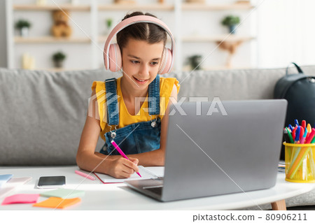 Girl sitting at desk, using laptop, drawing in copybook Girl sitting at desk, using laptop, drawing in copybook 80906211