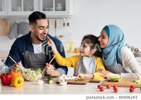 Taste It. Cute little arab girl feeding her daddy with cucumber slice Taste It. Cute little arab girl feeding her daddy with cucumber slice 80906265