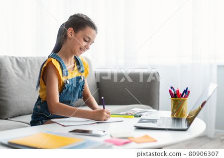 Girl sitting at desk, drawing in copybook 80906307
