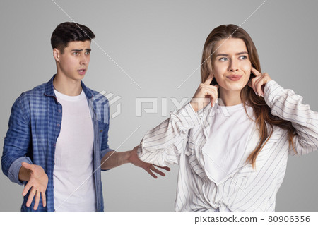 Quarrel and showdown. Sad woman covers her ears with fingers, upset man expresses negative emotions Quarrel and showdown. Sad woman covers her ears with fingers, upset man expresses negative emotions 80906356
