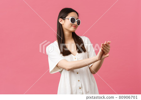 Beauty, people emotions and summer leisure and vacation concept. Smiling good-looking asian glamour girl looking at her manicure pleased after visiting nail studio, standing over pink background 80906701