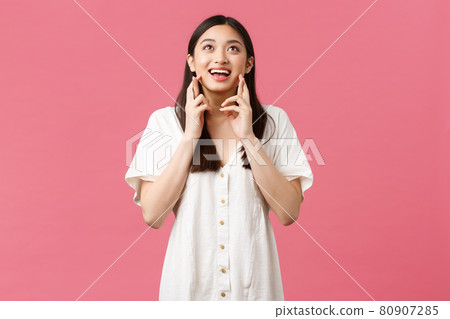 Beauty, people emotions and summer leisure concept. Dreamy asian girl in white dress making wish, looking hopeful sky as pleading god, cross fingers good luck, anticipating, pink background 80907285