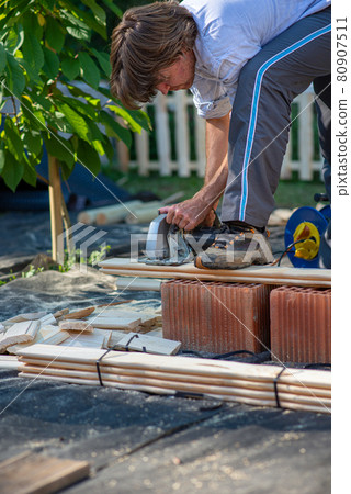 Young man working on a diy project outside in backyard 80907511